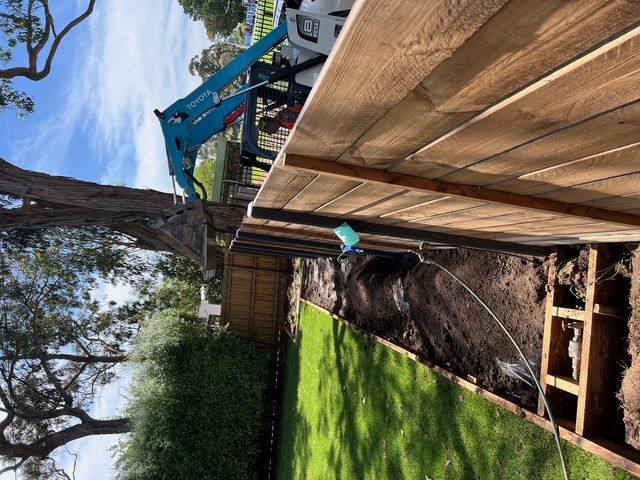 Timber retaining wall construction beside a green lawn